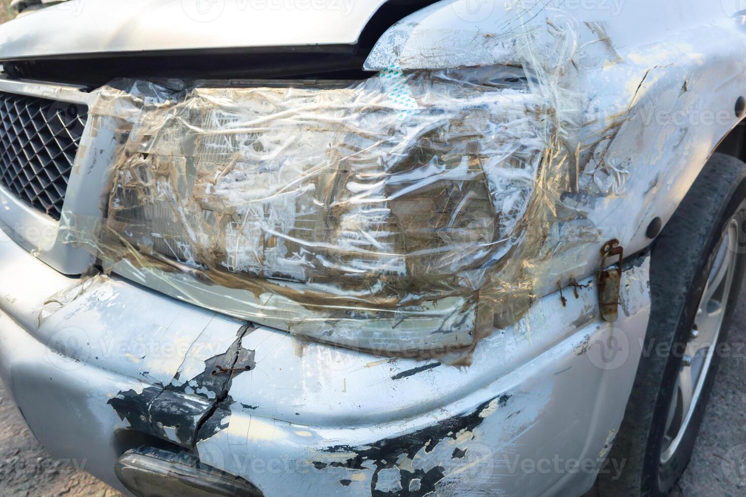 front side of an old damaged white vehicle headlamp fixed with clear tape photo