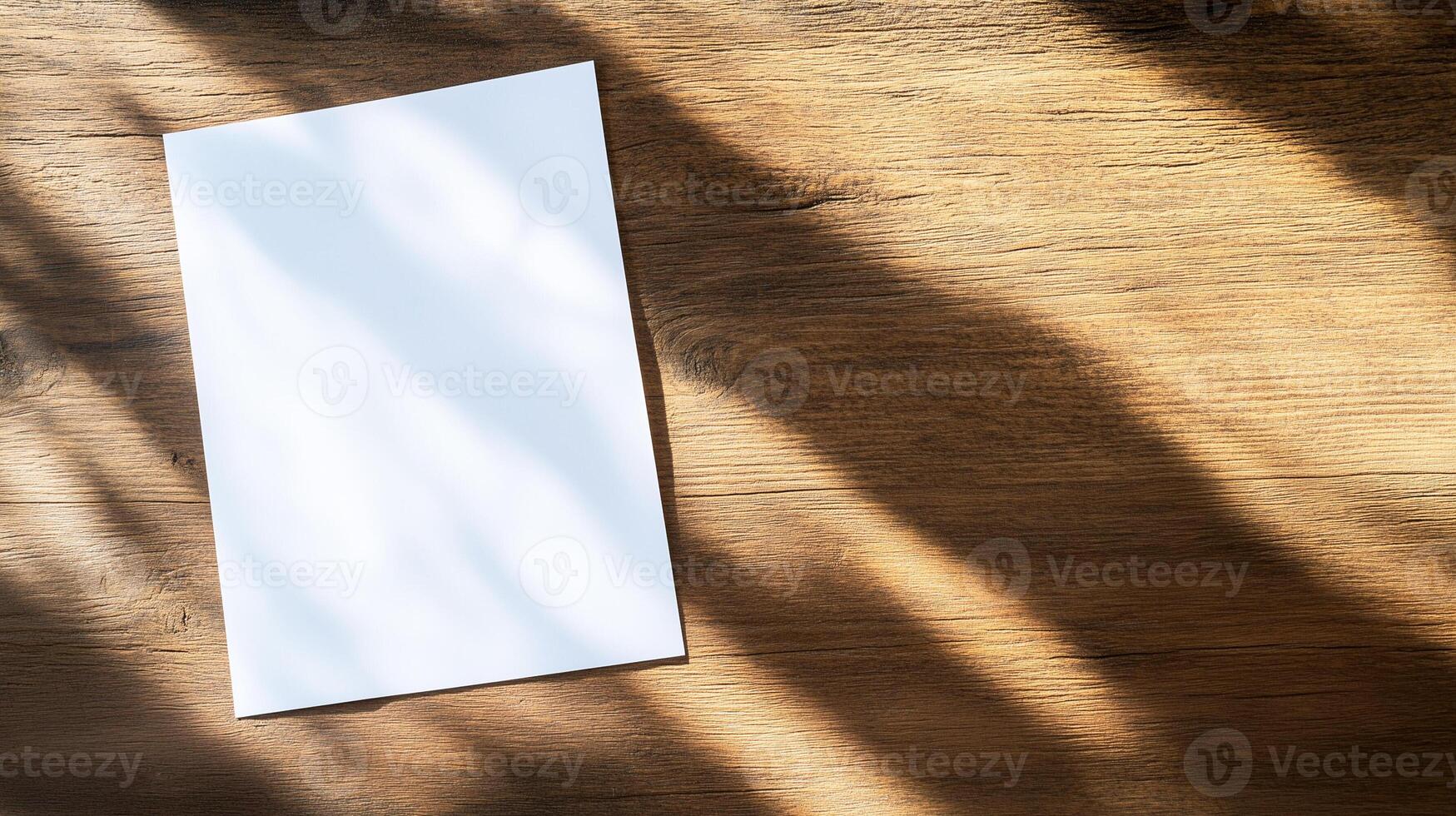 Blank paper sheet on wooden table with shadow and sunlight photo
