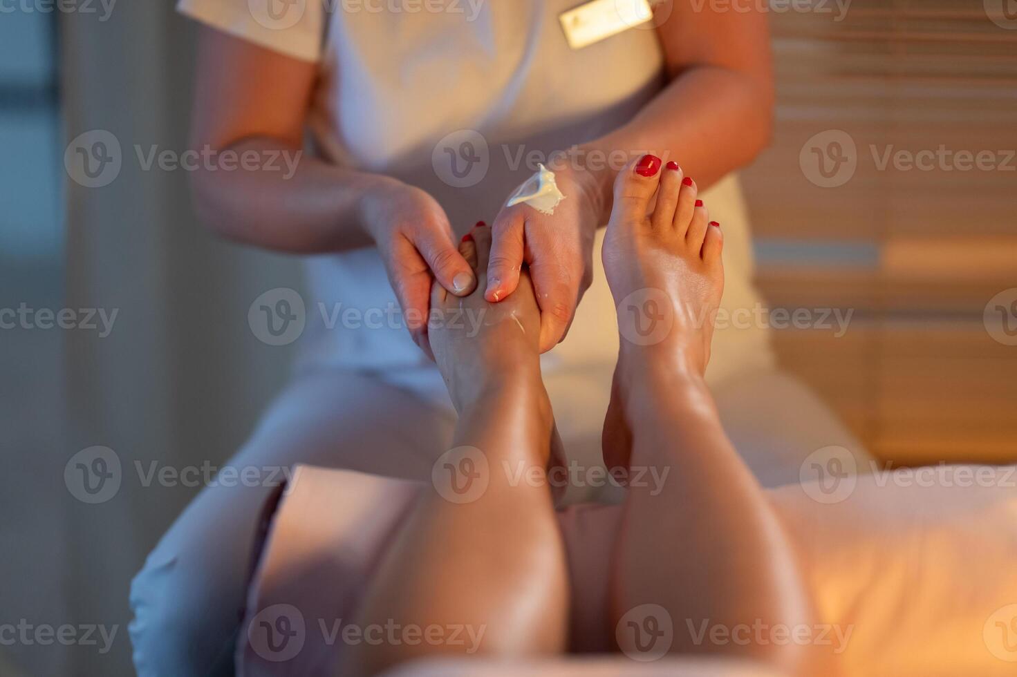 Foot Massage Therapy in a Relaxing Spa Setting. A professional massage therapist in a white uniform provides a soothing foot massage to a client in a calm and serene spa environment photo