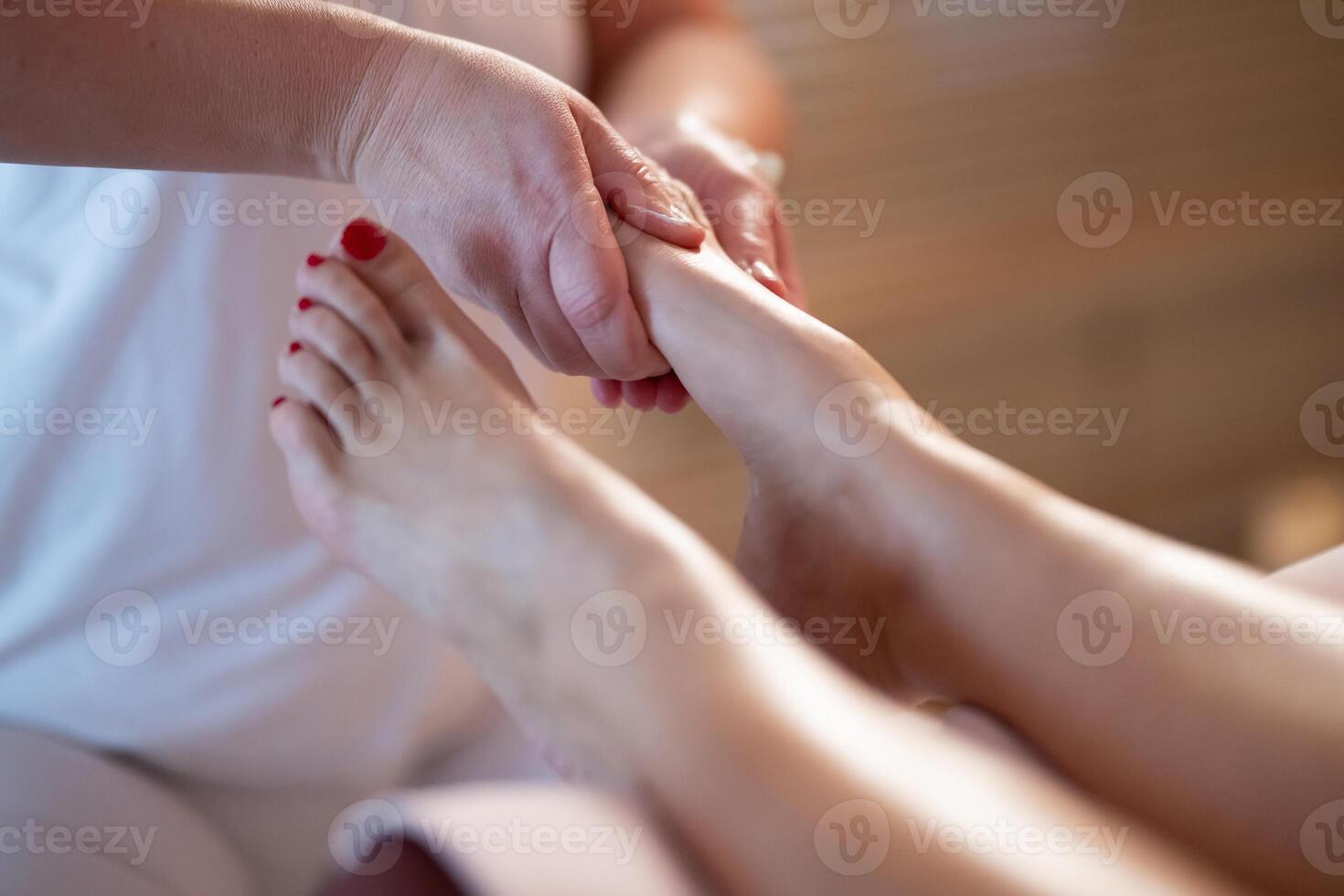 Foot Massage Therapy in a Relaxing Spa Setting. A professional massage therapist in a white uniform provides a soothing foot massage to a client in a calm and serene spa environment photo