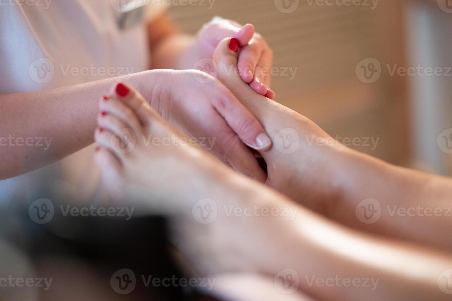 Foot Massage Therapy in a Relaxing Spa Setting. A professional massage therapist in a white uniform provides a soothing foot massage to a client in a calm and serene spa environment photo