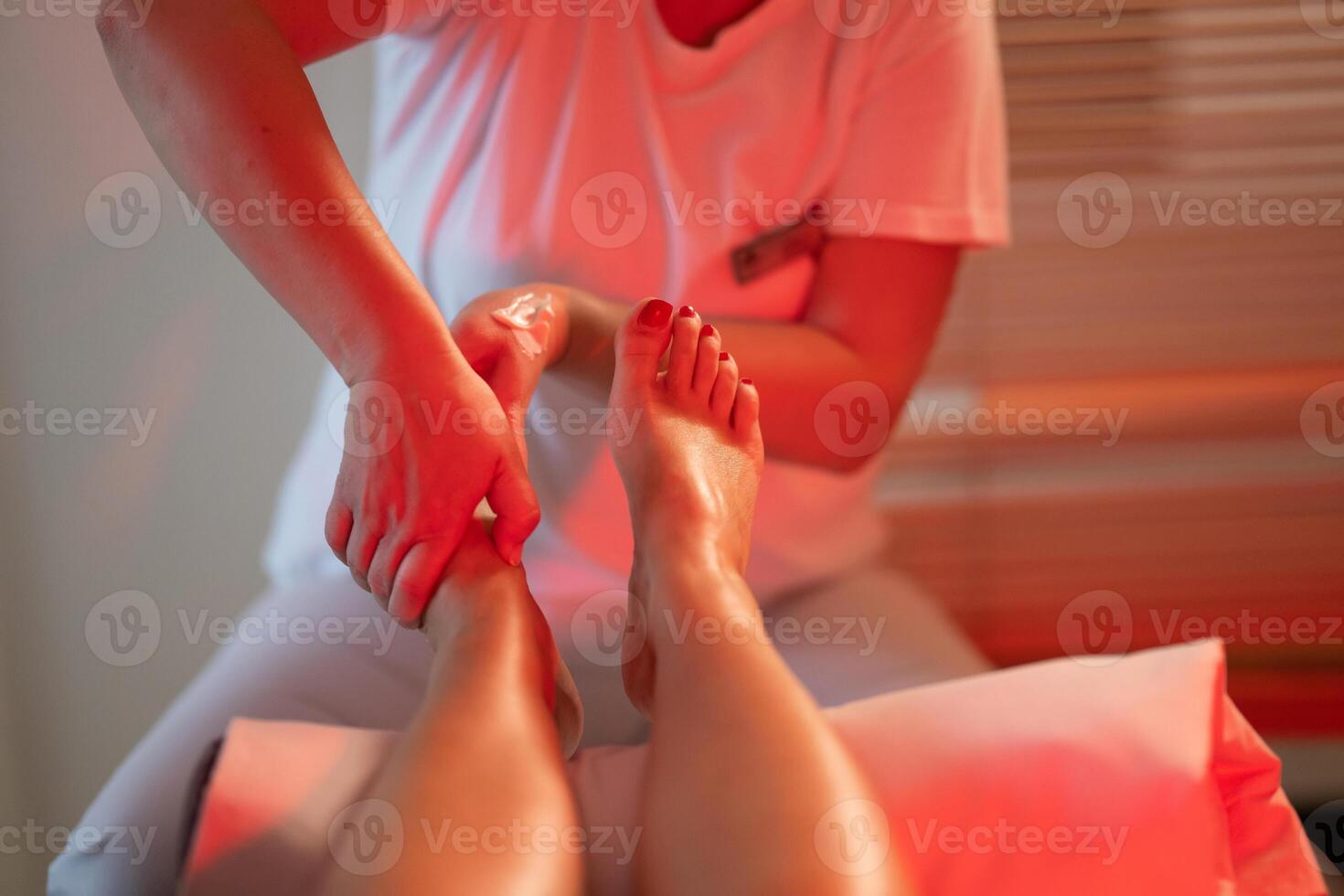 Foot Massage Therapy in a Relaxing Spa Setting. A professional massage therapist in a white uniform provides a soothing foot massage to a client in a calm and serene spa environment photo