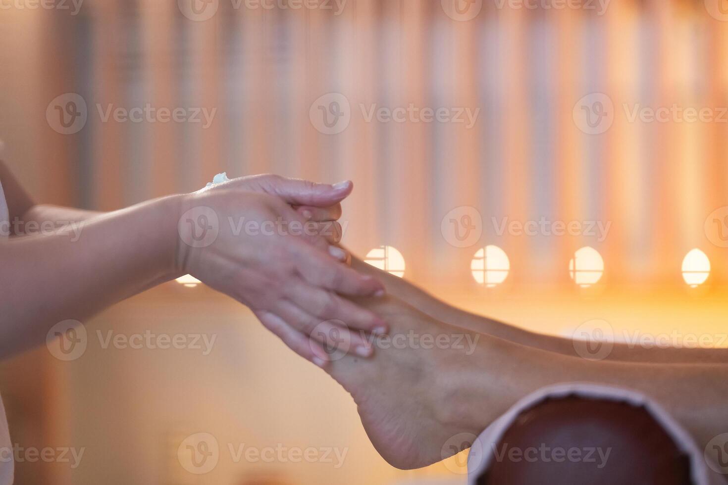 Foot Massage Therapy in a Relaxing Spa Setting. A professional massage therapist in a white uniform provides a soothing foot massage to a client in a calm and serene spa environment photo
