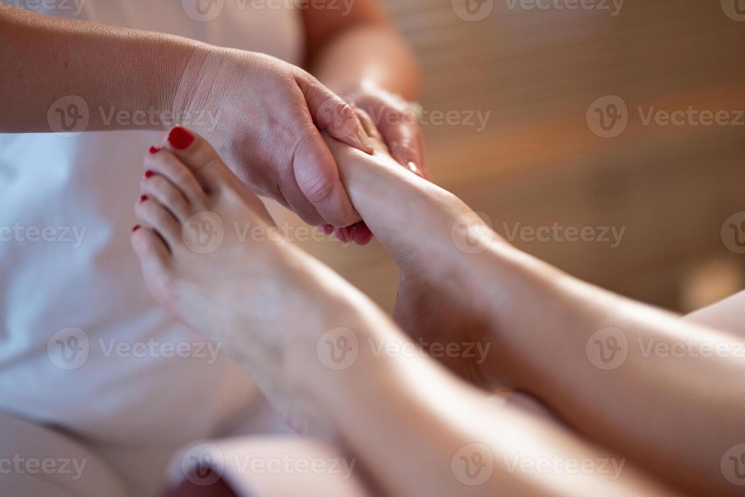 Foot Massage Therapy in a Relaxing Spa Setting. A professional massage therapist in a white uniform provides a soothing foot massage to a client in a calm and serene spa environment photo
