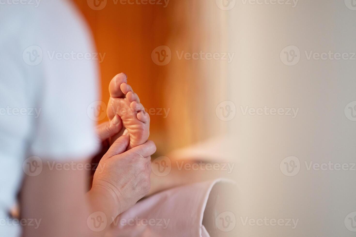Foot Massage Therapy in a Relaxing Spa Setting. A professional massage therapist in a white uniform provides a soothing foot massage to a client in a calm and serene spa environment photo