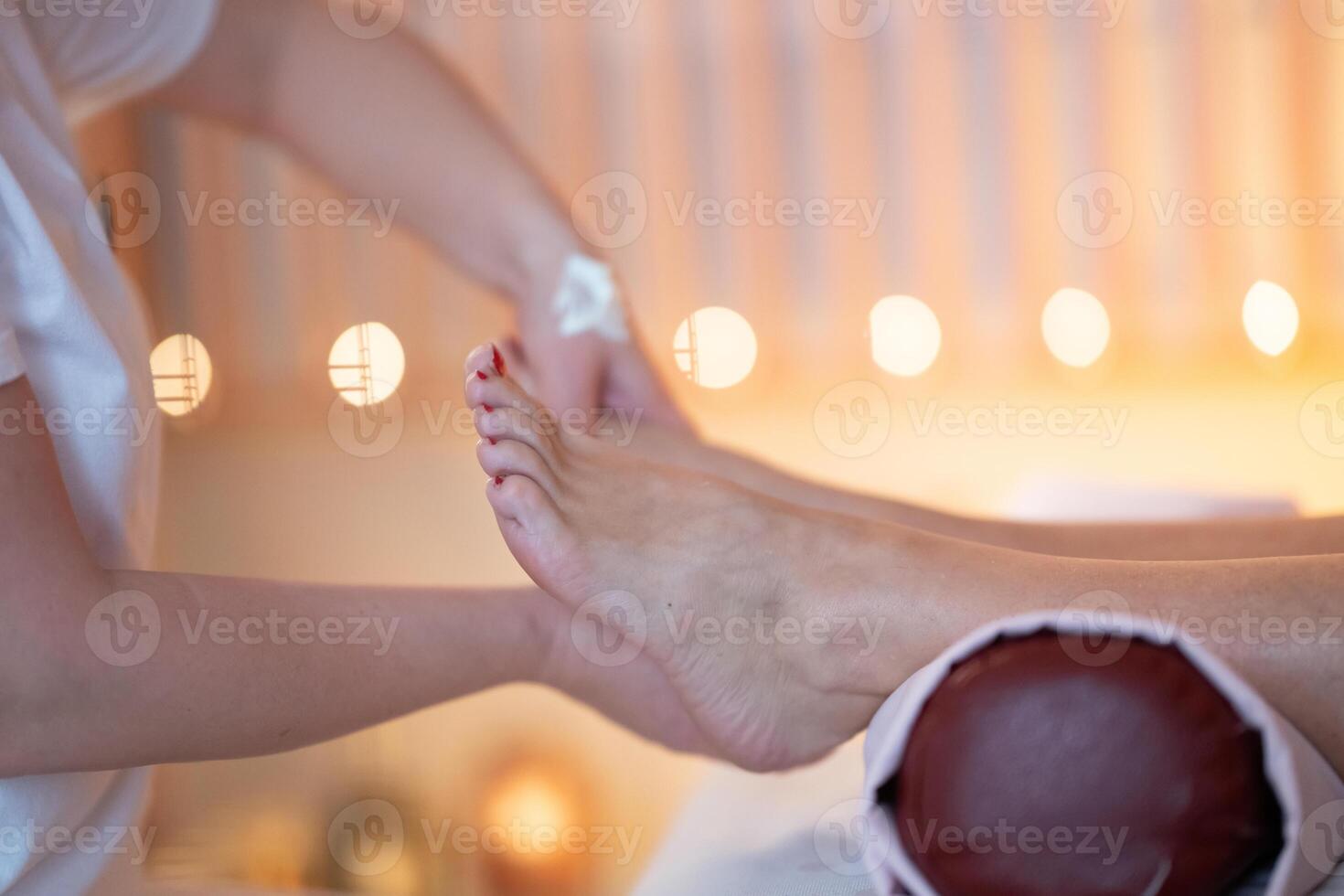 Foot Massage Therapy in a Relaxing Spa Setting. A professional massage therapist in a white uniform provides a soothing foot massage to a client in a calm and serene spa environment photo