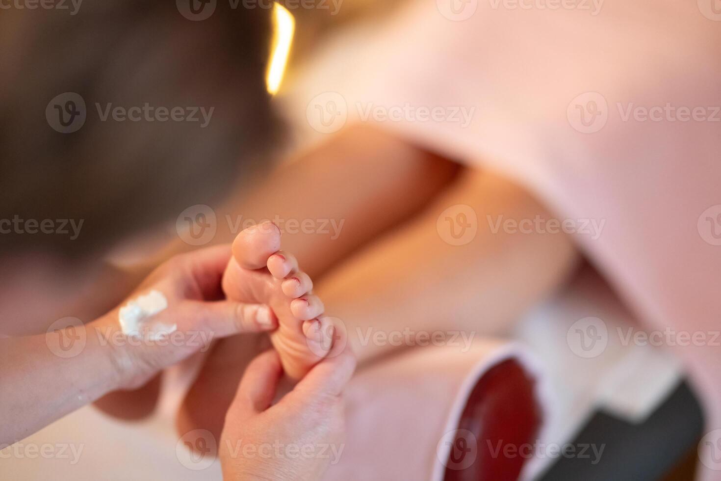 Foot Massage Therapy in a Relaxing Spa Setting. A professional massage therapist in a white uniform provides a soothing foot massage to a client in a calm and serene spa environment photo