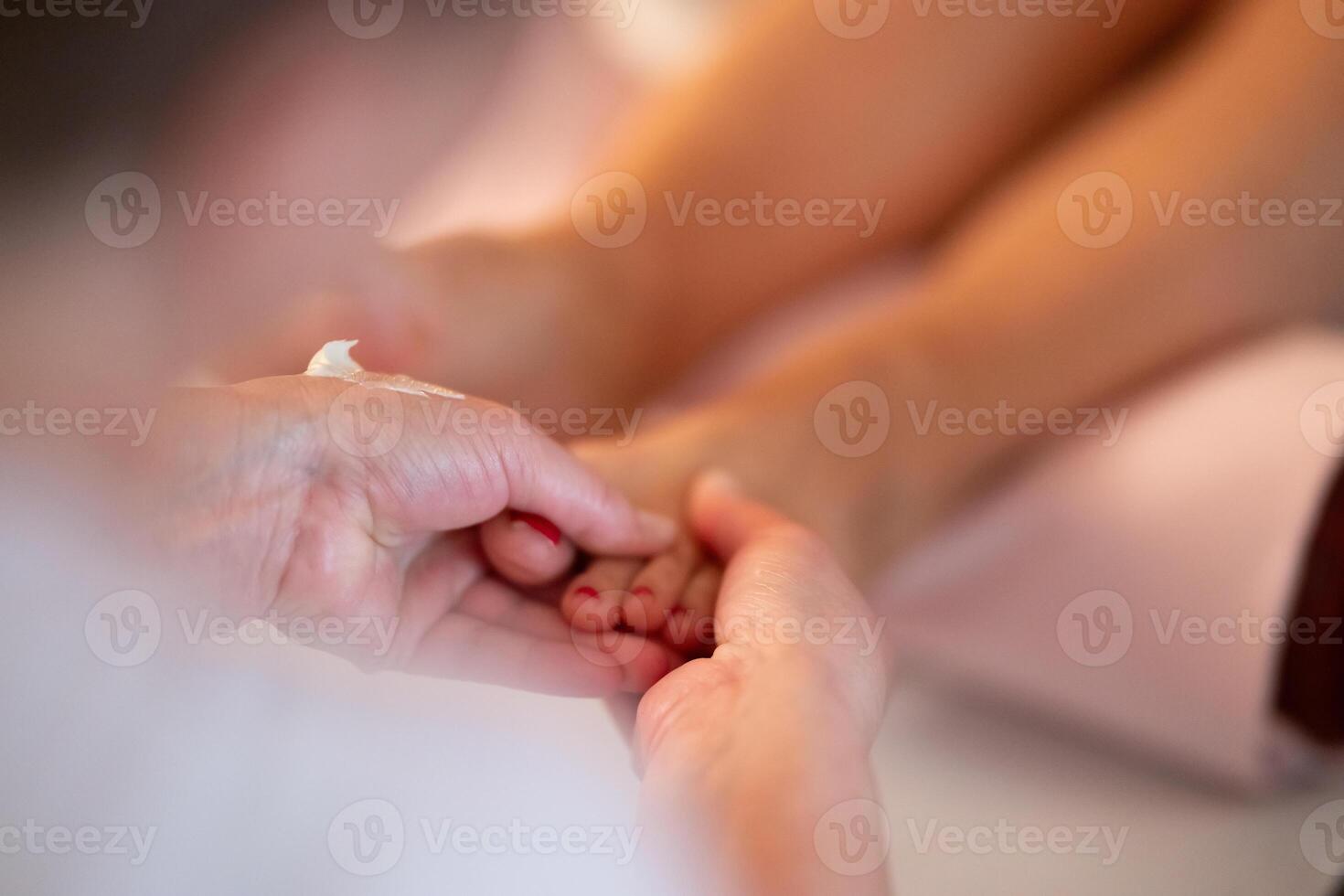 Foot Massage Therapy in a Relaxing Spa Setting. A professional massage therapist in a white uniform provides a soothing foot massage to a client in a calm and serene spa environment photo