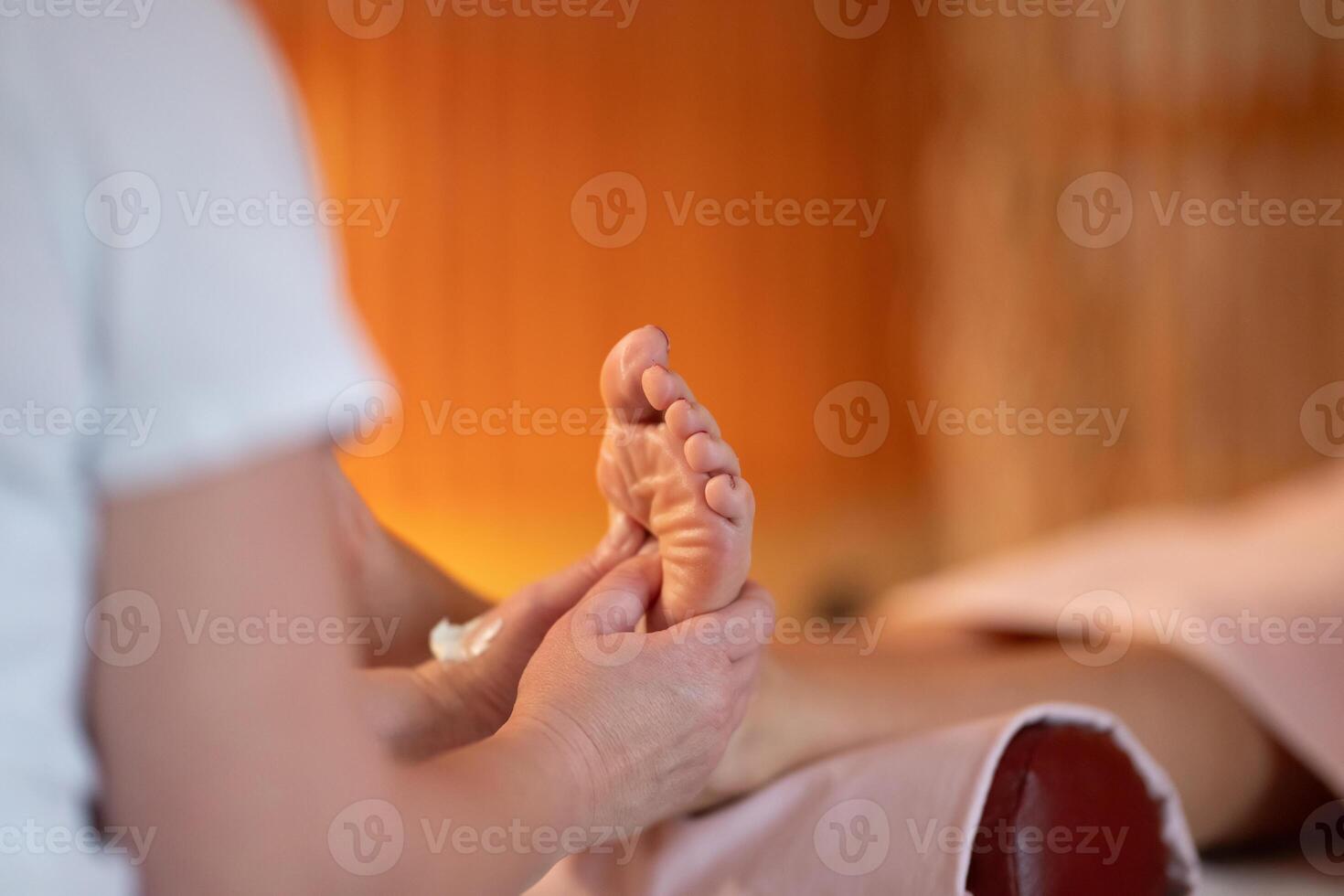 Foot Massage Therapy in a Relaxing Spa Setting. A professional massage therapist in a white uniform provides a soothing foot massage to a client in a calm and serene spa environment photo