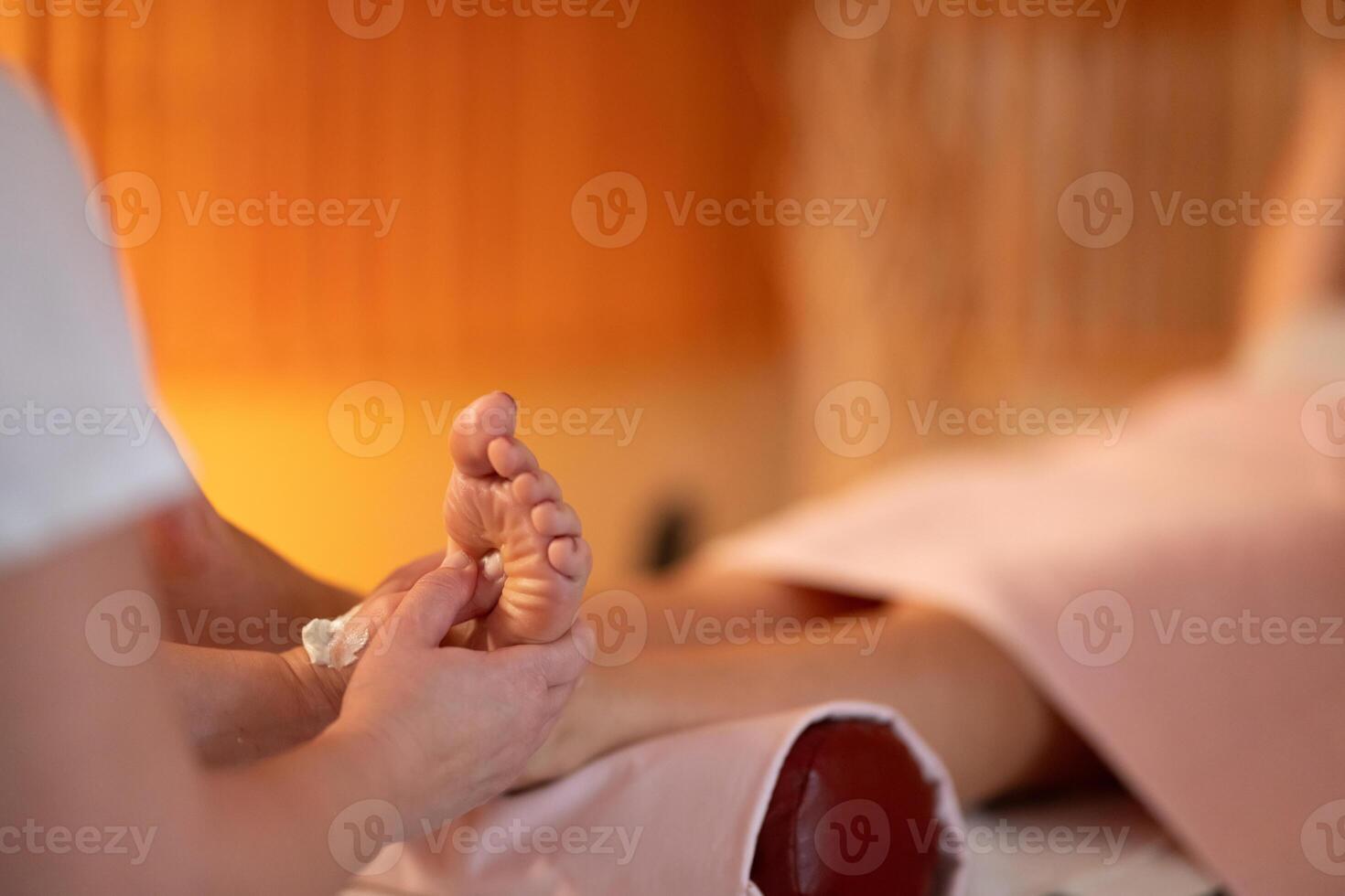 Foot Massage Therapy in a Relaxing Spa Setting. A professional massage therapist in a white uniform provides a soothing foot massage to a client in a calm and serene spa environment photo
