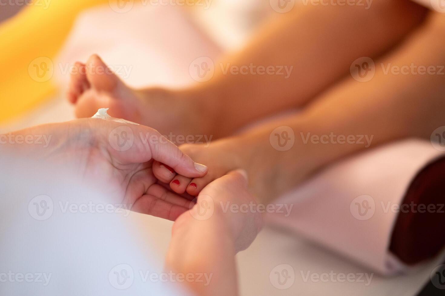 Foot Massage Therapy in a Relaxing Spa Setting. A professional massage therapist in a white uniform provides a soothing foot massage to a client in a calm and serene spa environment photo