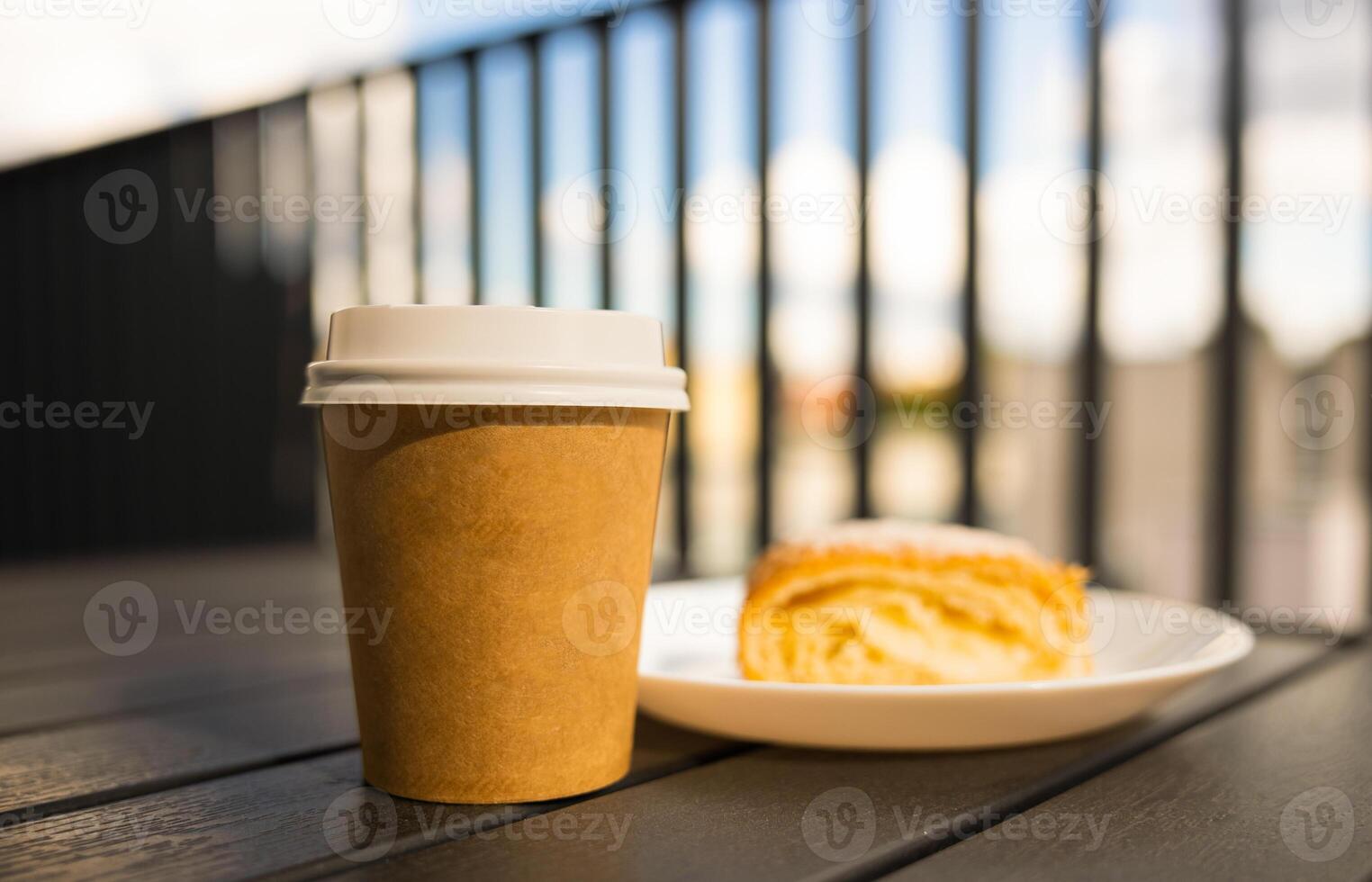 A paper cup of coffee with a white lid the table next the pie Cafe open veranda photo
