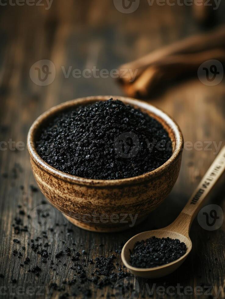 Black cumin seeds in a bowl with a wooden spoon on a wooden table photo