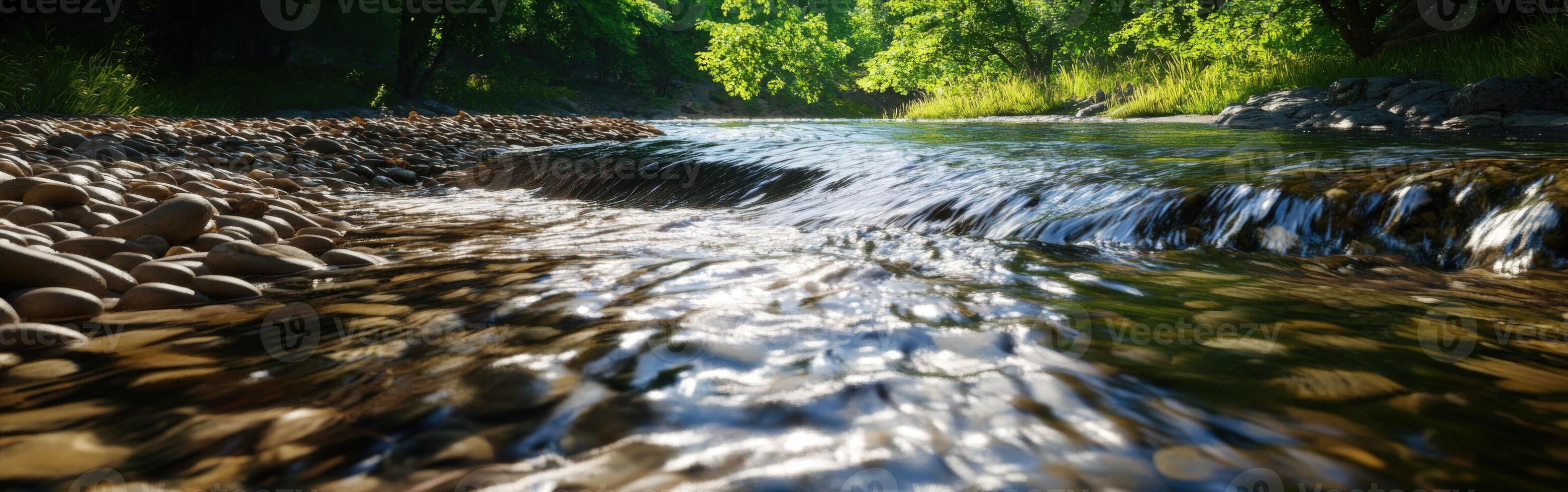 River water flows over pebbles under sunlight in serene landscape photo