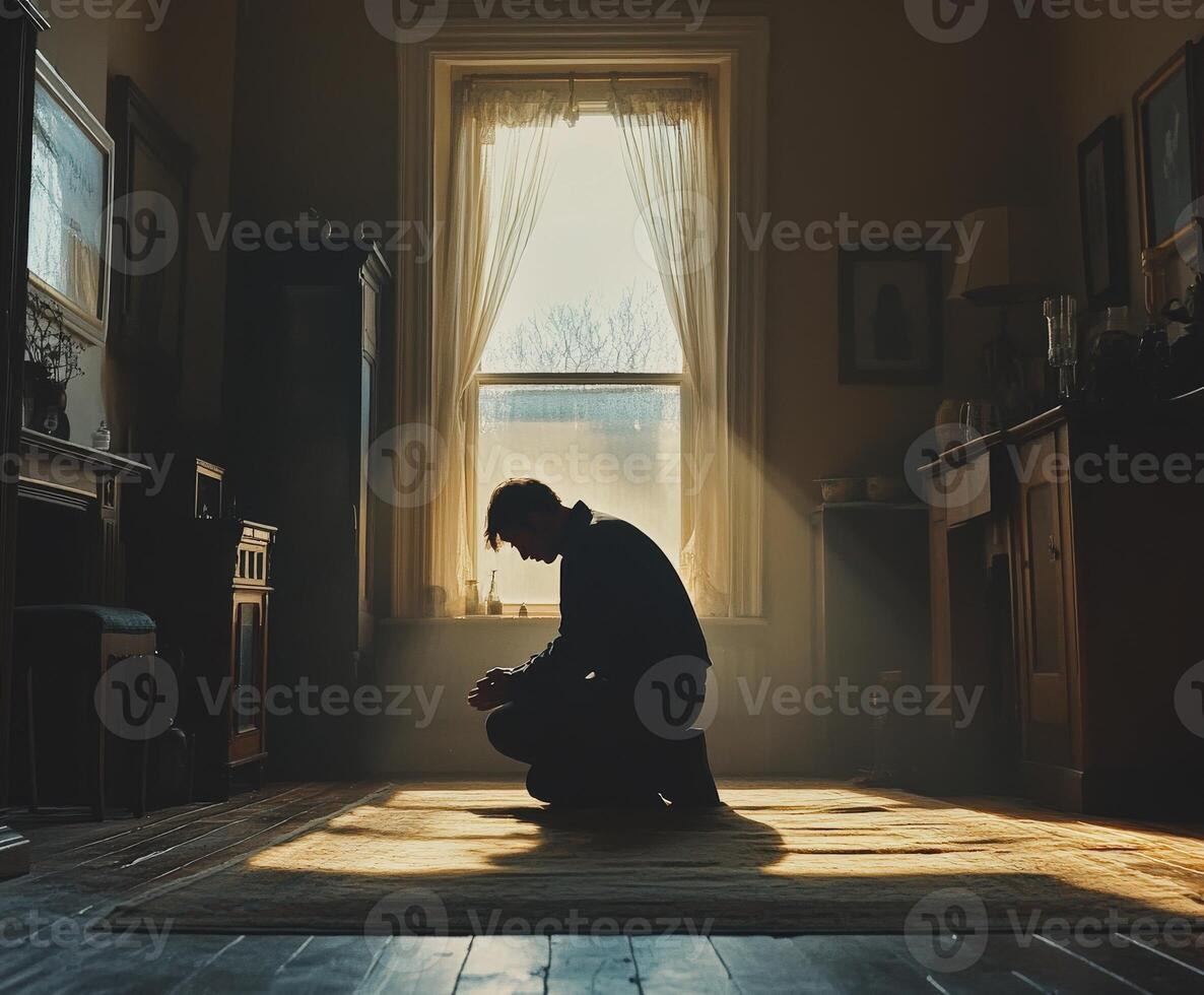 Man kneeling in a sunlit room reflecting on a quiet moment photo