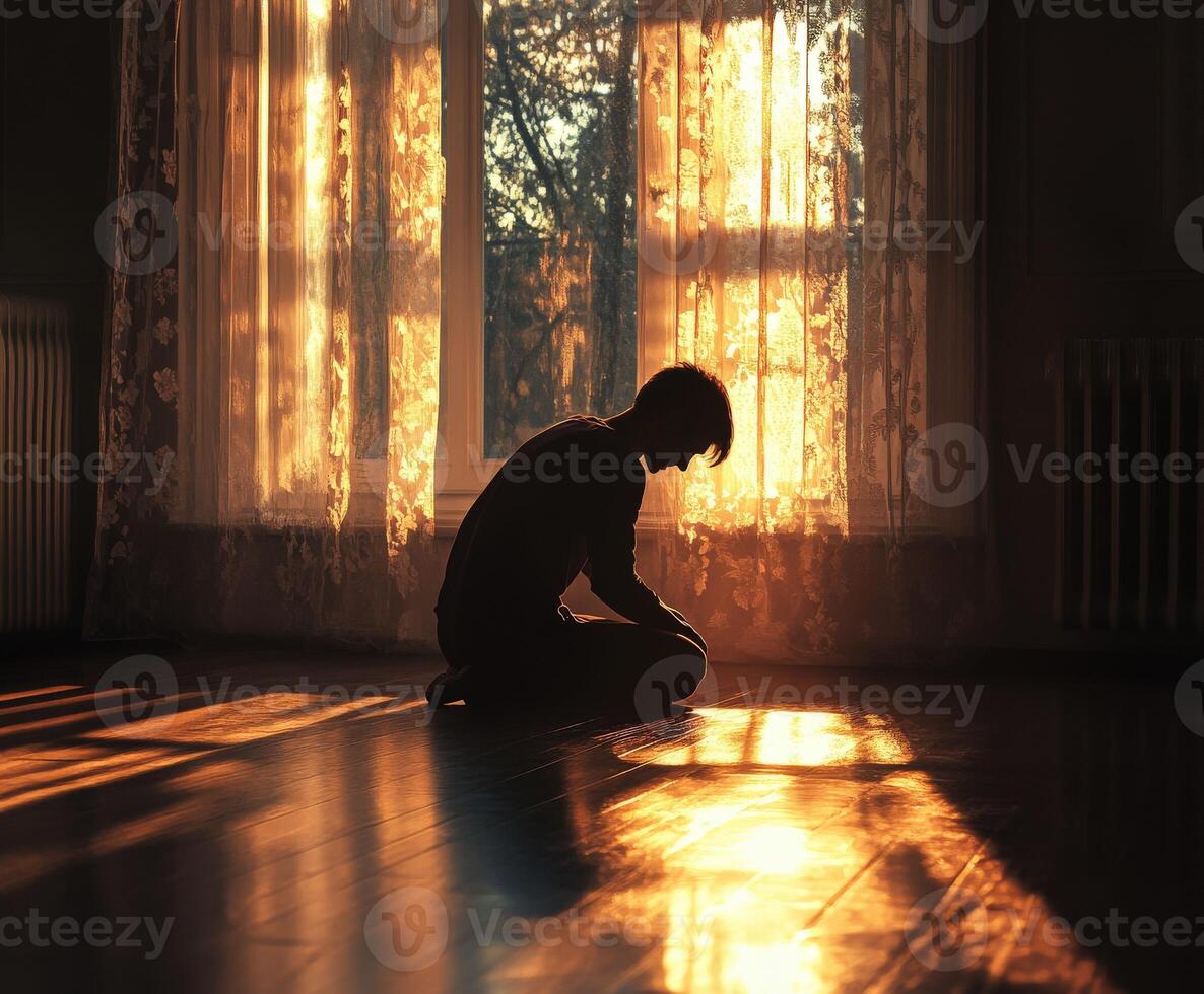 Boy sits in quiet contemplation during sunset in a warm room photo