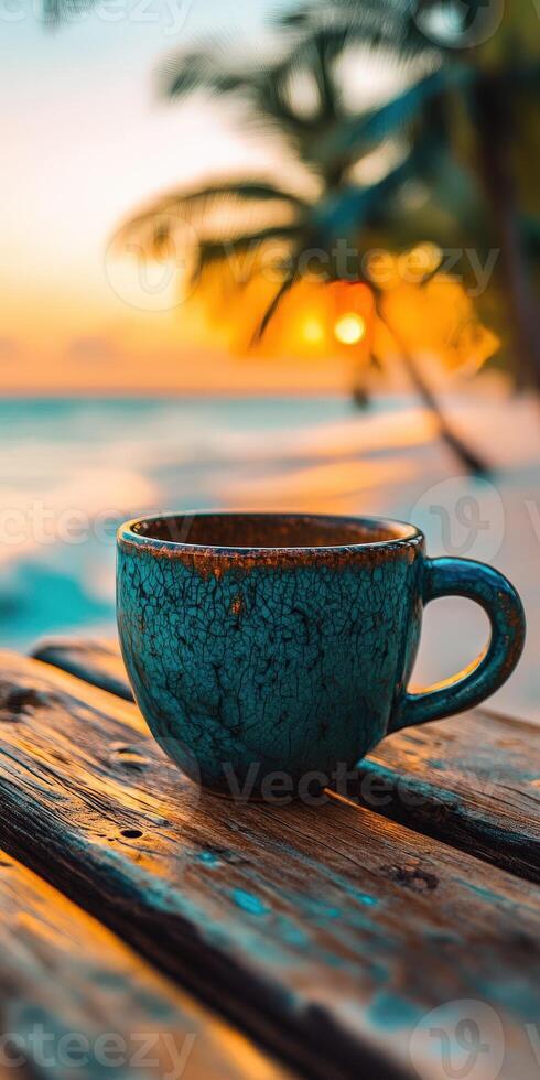 Warm cup of coffee rests on a wooden table at sunset by the beach with palm trees in the background photo