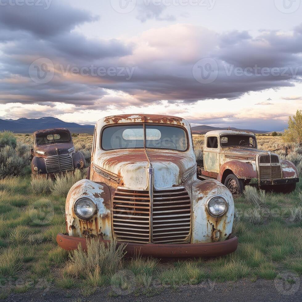 Classic trucks rust away in a scenic landscape under dramatic clouds at sunset photo