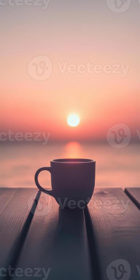 Coffee cup on wooden table with sunset in background photo