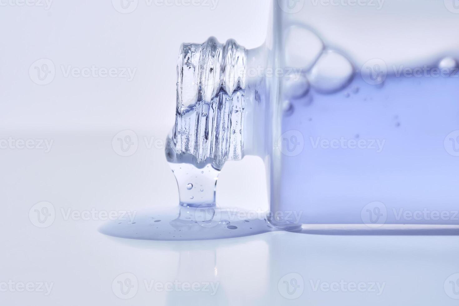 A cosmetic bottle from which a blue emulsion is poured. photo