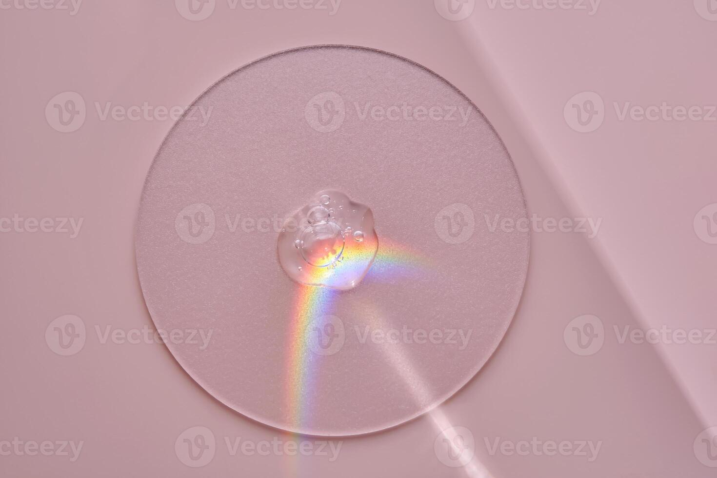 A drop of serum on a round stand on a pink background with beautiful caustics. photo