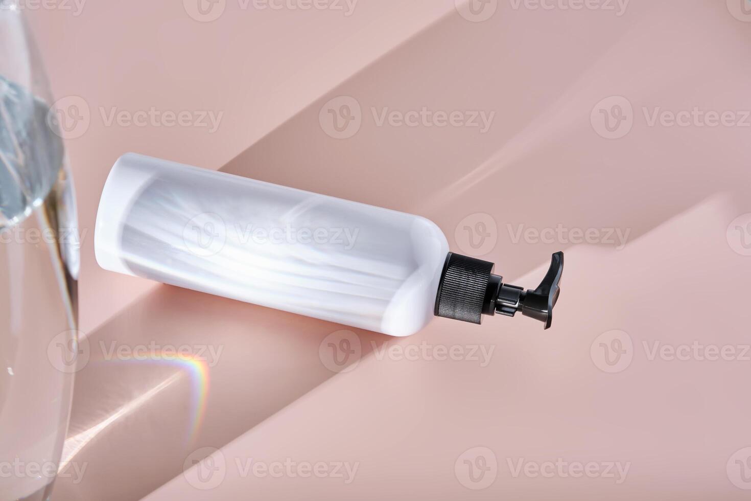 White bottles of bath product on a powdery pink background. photo