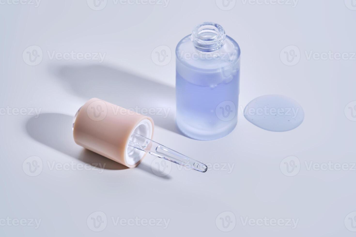 Cosmetic bottle, dropper and a drop of serum on a white background. photo