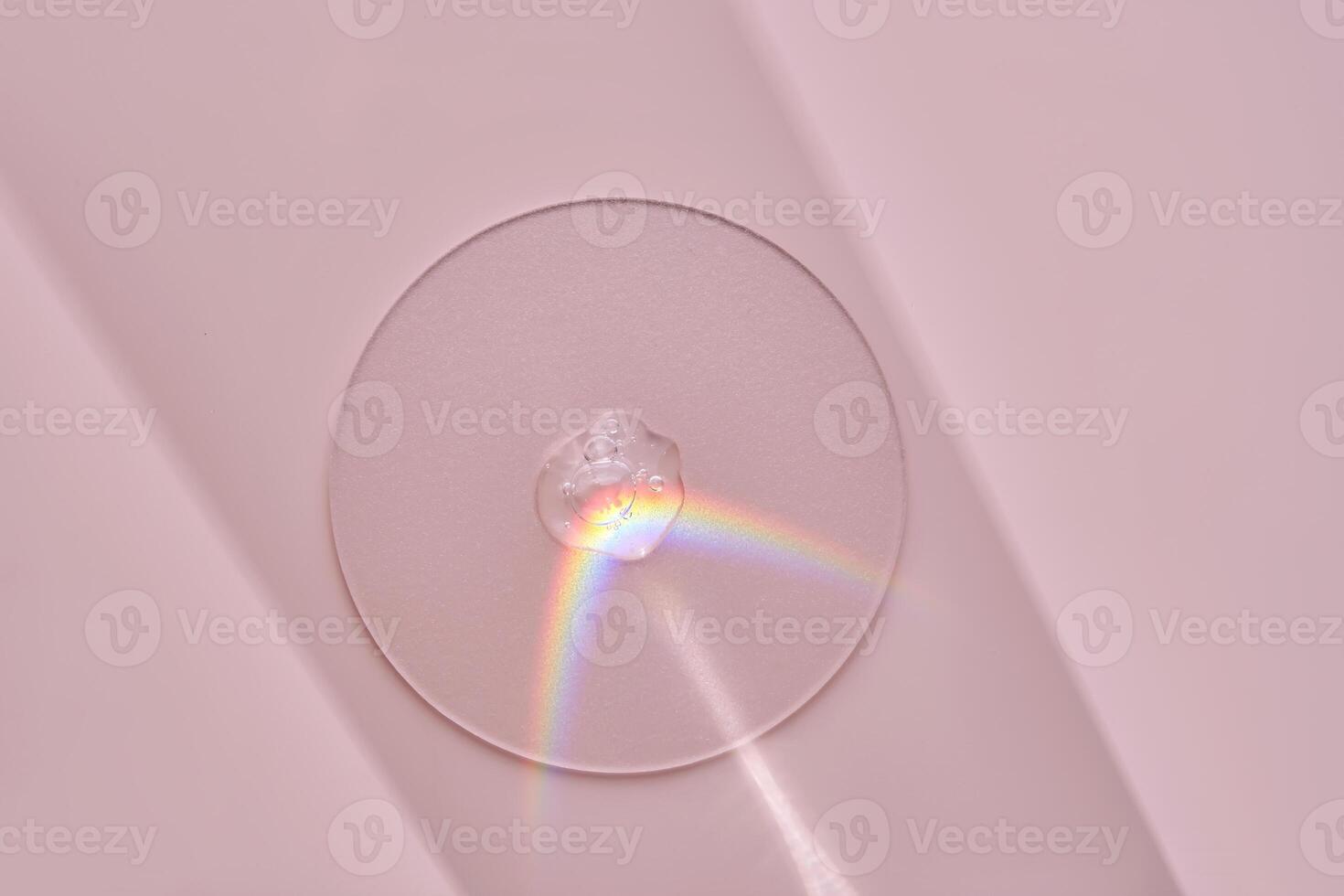 A drop of serum on a round stand on a pink background with beautiful caustics. photo