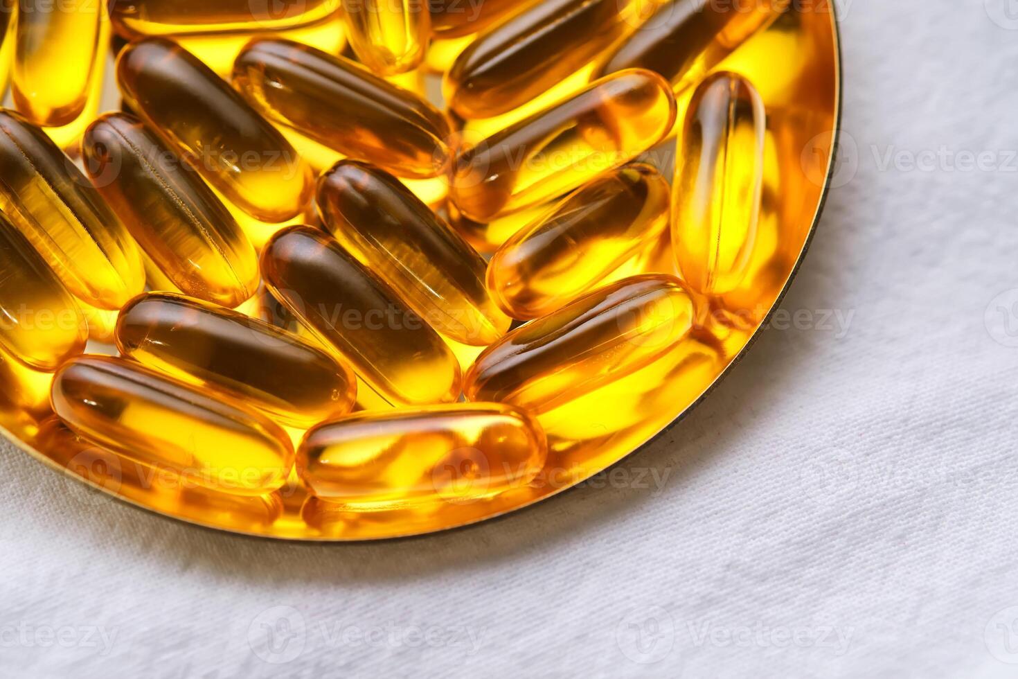 Yellow capsules with Omega-3 fish oil on a golden tray. photo
