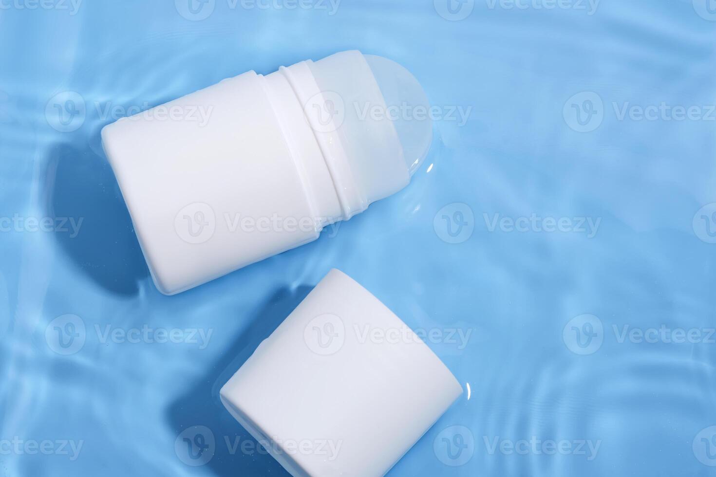 Roll-on deodorant on a blue background in water. photo