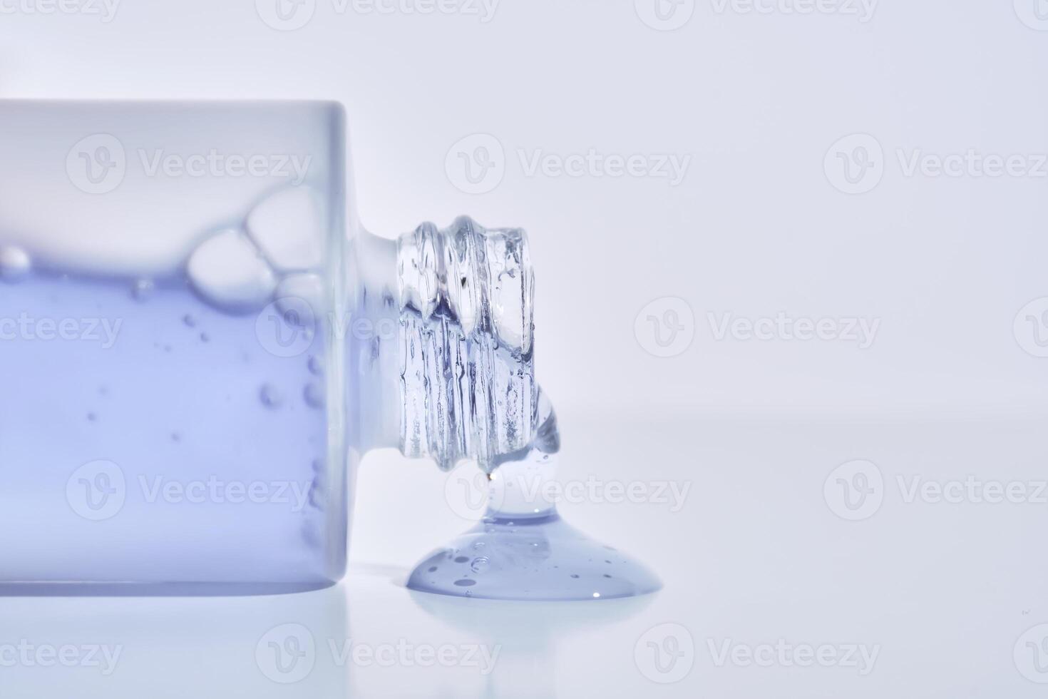 A cosmetic bottle from which a blue emulsion is poured. photo