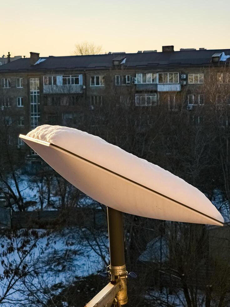 SpaceX's Starlink satellite dish is covered in snow. Starlink is disabled and does not melt snow. Vertical photo