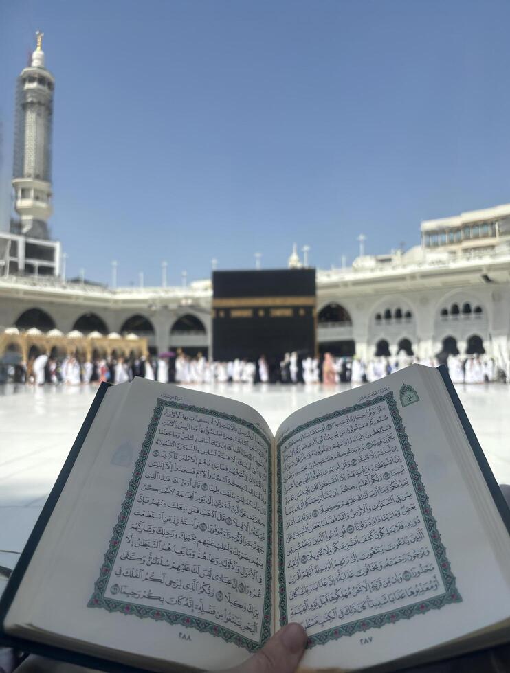 Mekkah, Saudia Arabia, 02 May 2024, A Quran reading in front of the Kaaba at Masjid al-Haram, Mecca, Saudi Arabia. Worshippers perform Tawaf around the sacred site under a clear blue sky, symbolizing photo