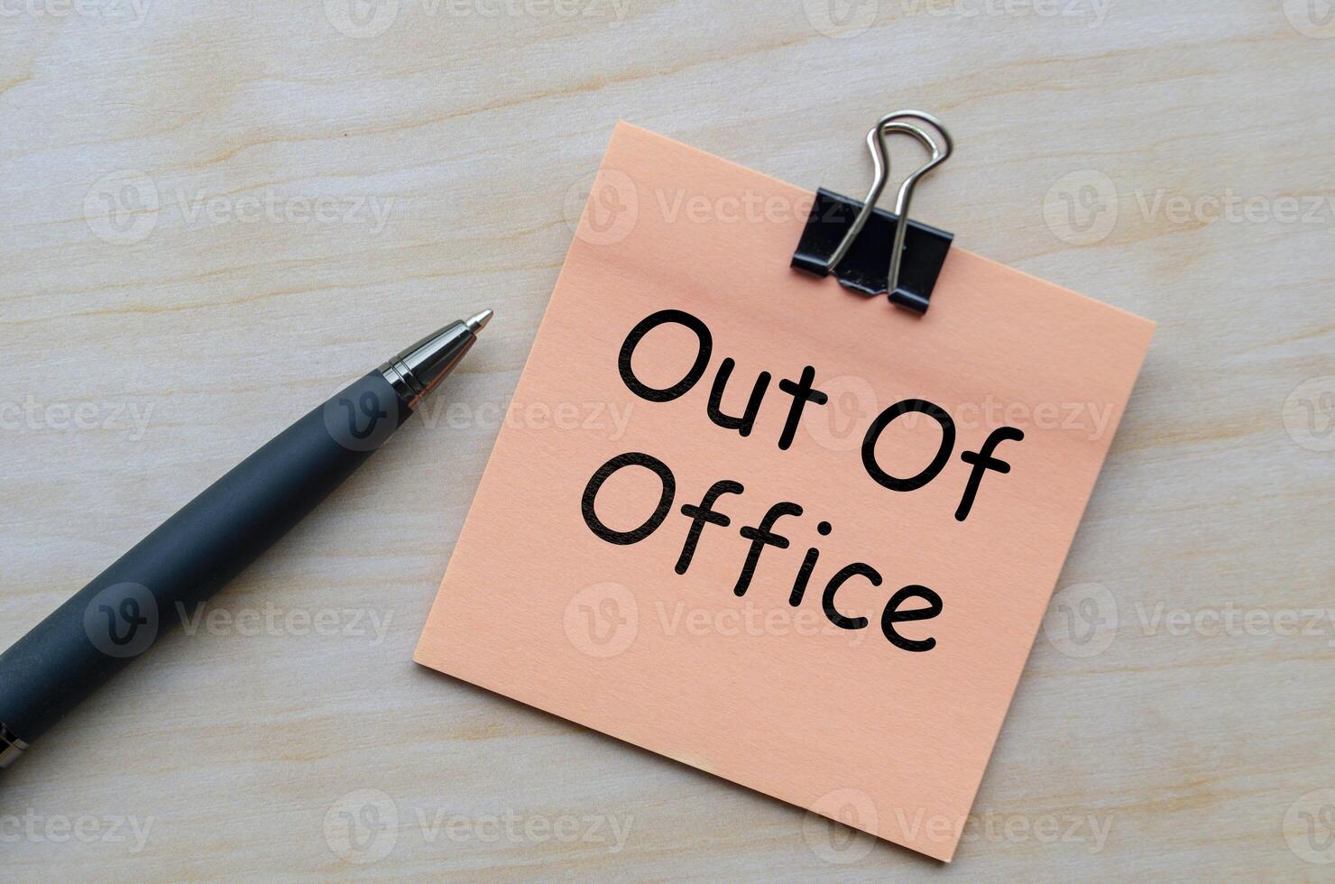 Top view of out of office text on notepad on wooden table photo
