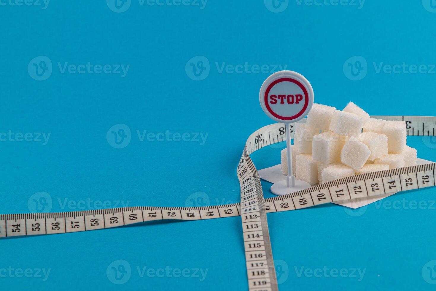 Sugar cubes with a stop sign and measuring tape on a blue background photo