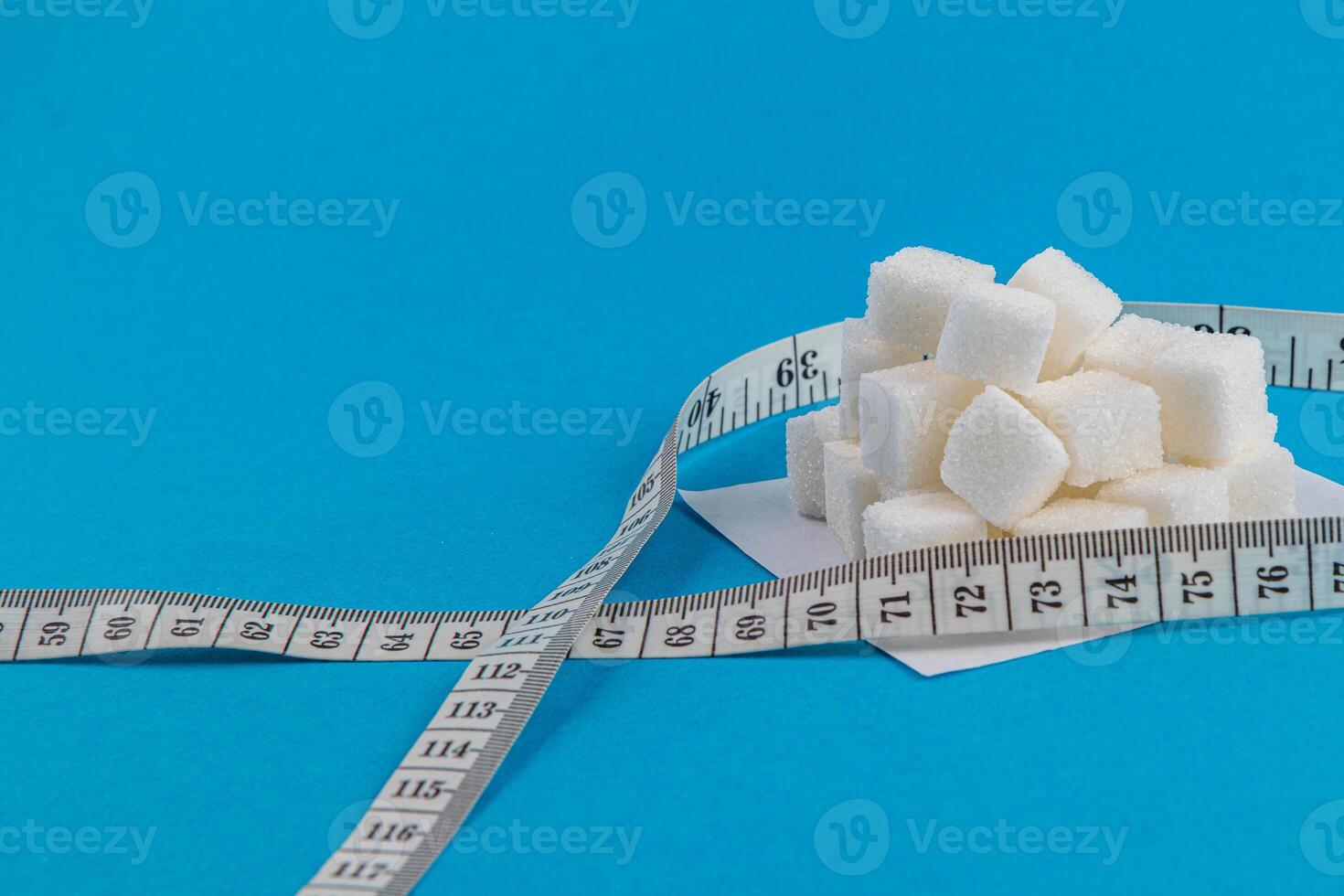 Sugar cubes with measuring tape on a blue background for kitchen use photo