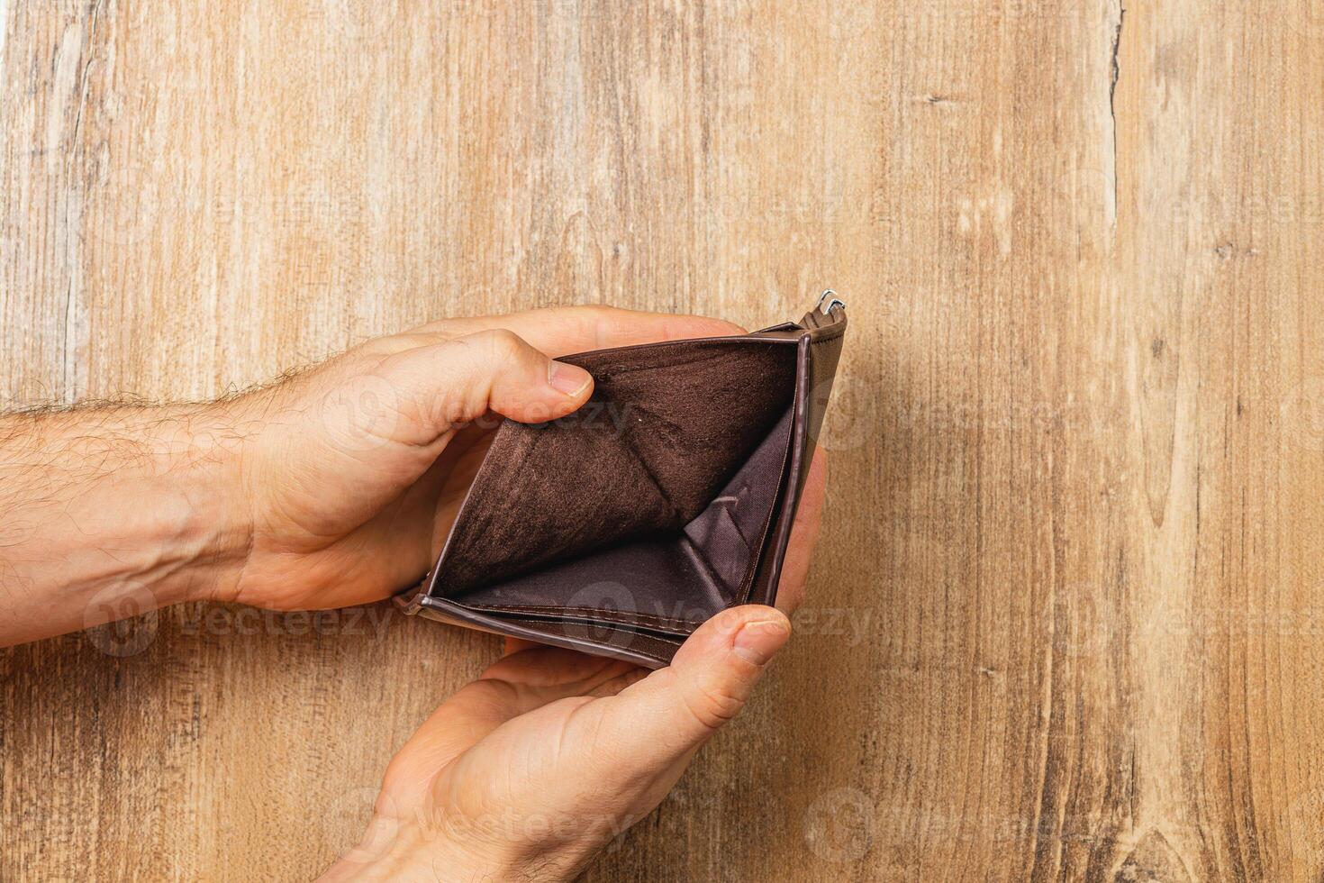 Struggling businessman examines empty wallet while facing financial crisis photo