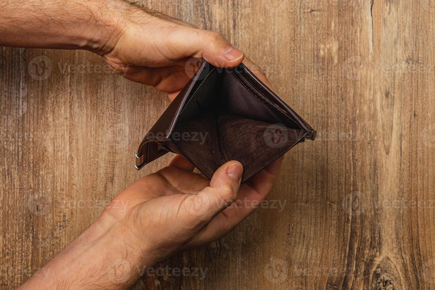 Man holds empty wallet while facing financial crisis and uncertainty photo