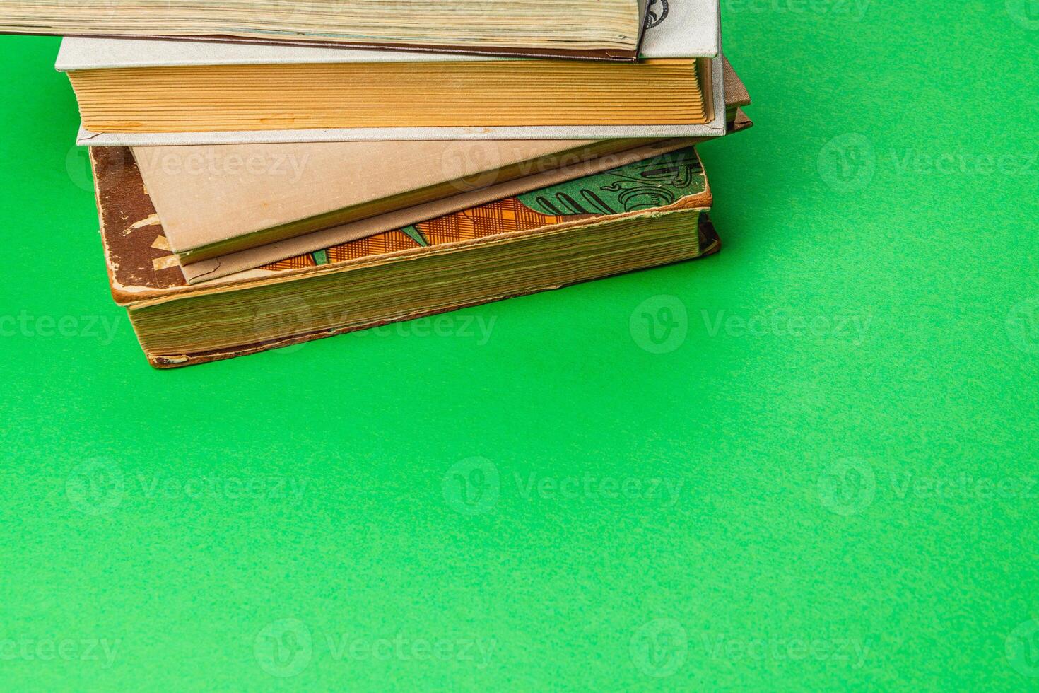 Stacked vintage books on a vibrant green background in natural light photo