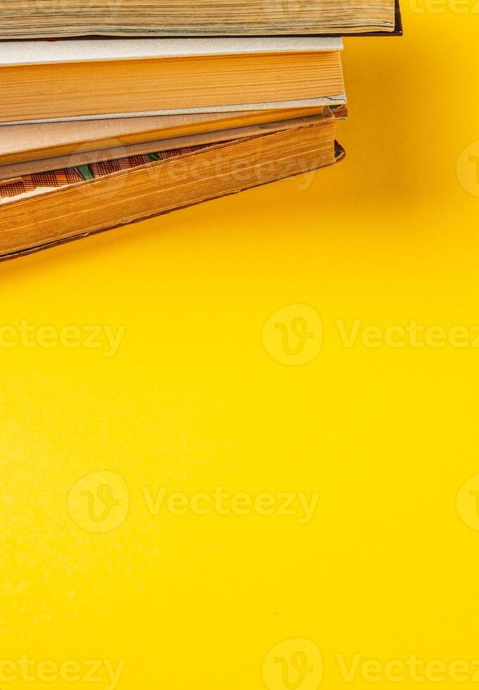 Stacked old books on a bright yellow surface for a vibrant study atmosphere photo