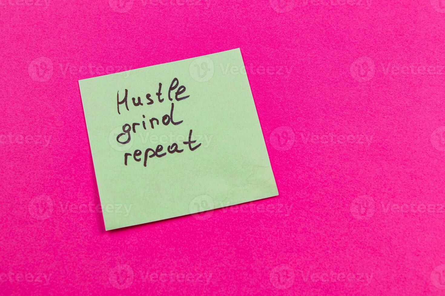 Motivational sticky note on pink highlights hustle and determination photo