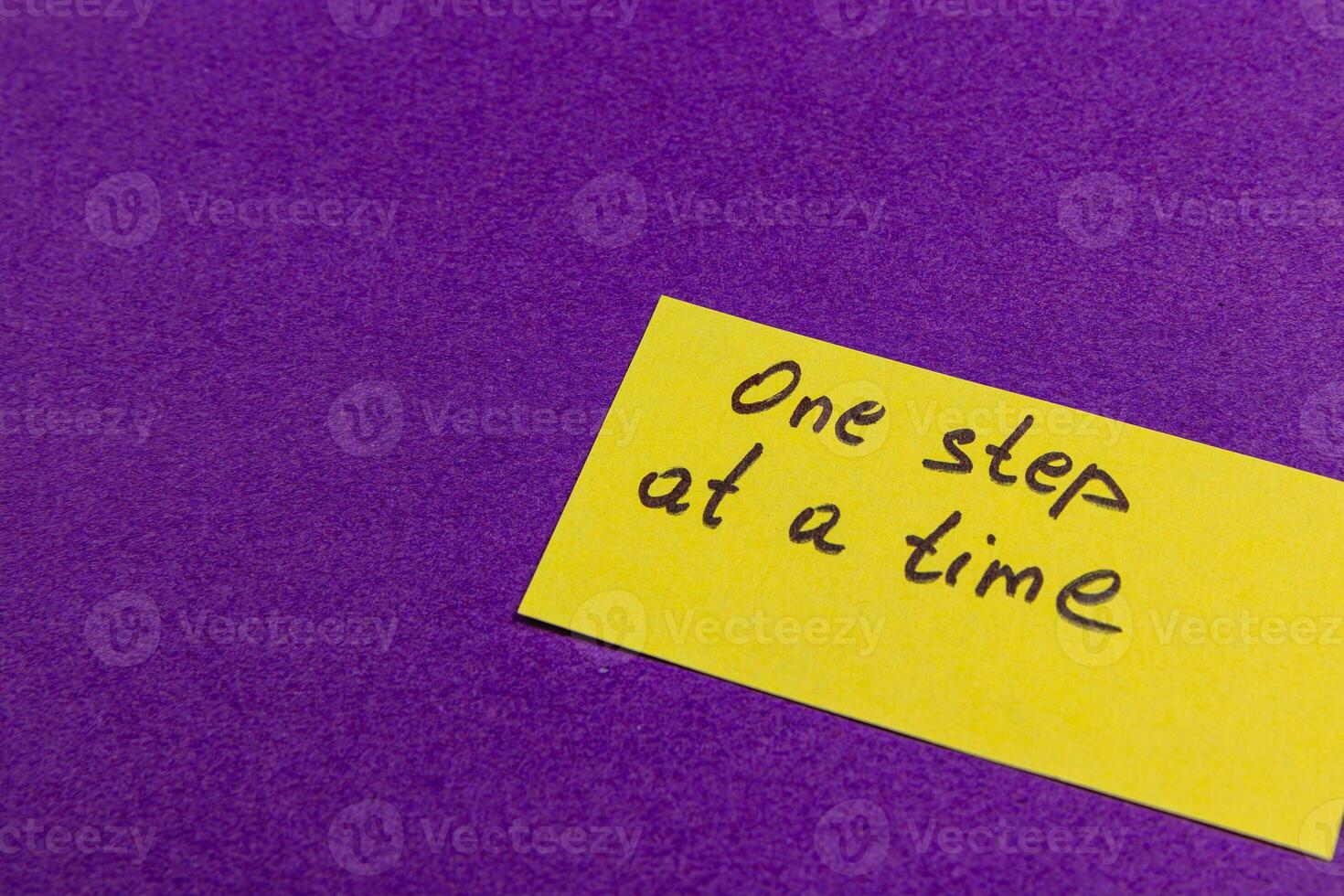 Motivational reminder on yellow sticky note placed on purple background photo