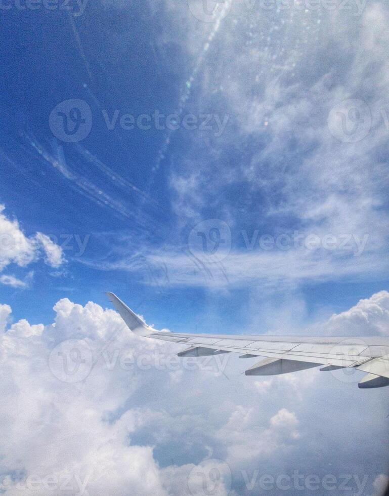Airplane Wing Above Fluffy Clouds Serene Blue Sky View photo