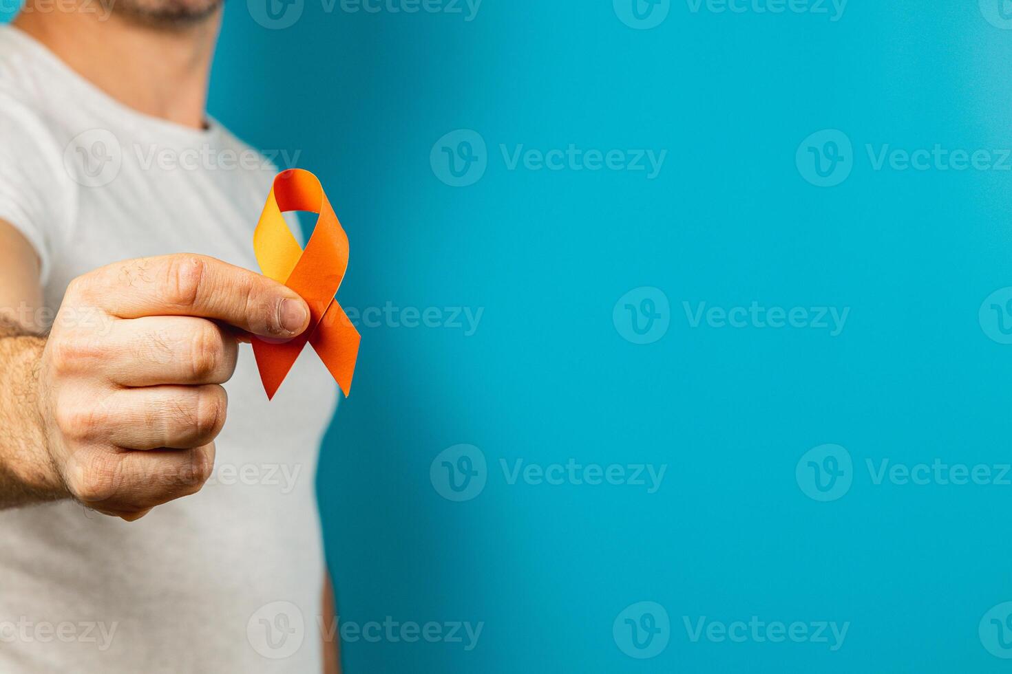 Person holds orange ribbon for mental health on blue background photo