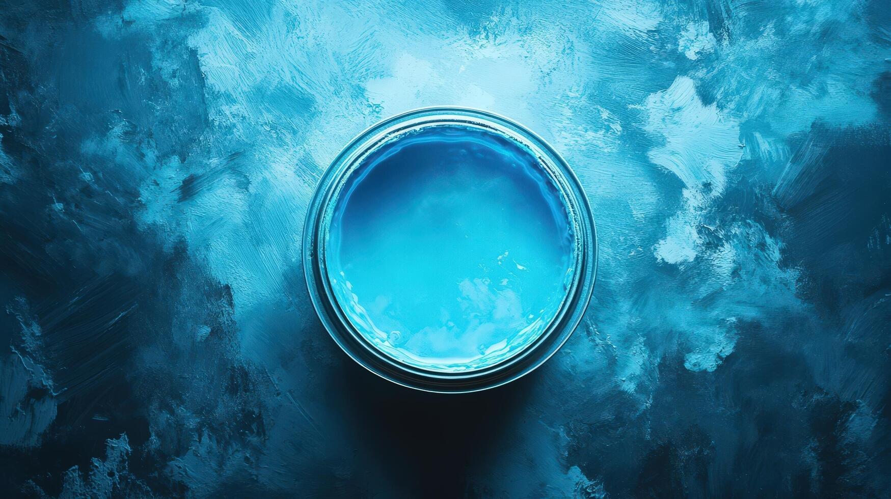 A can of vibrant blue paint sits on a textured surface photo