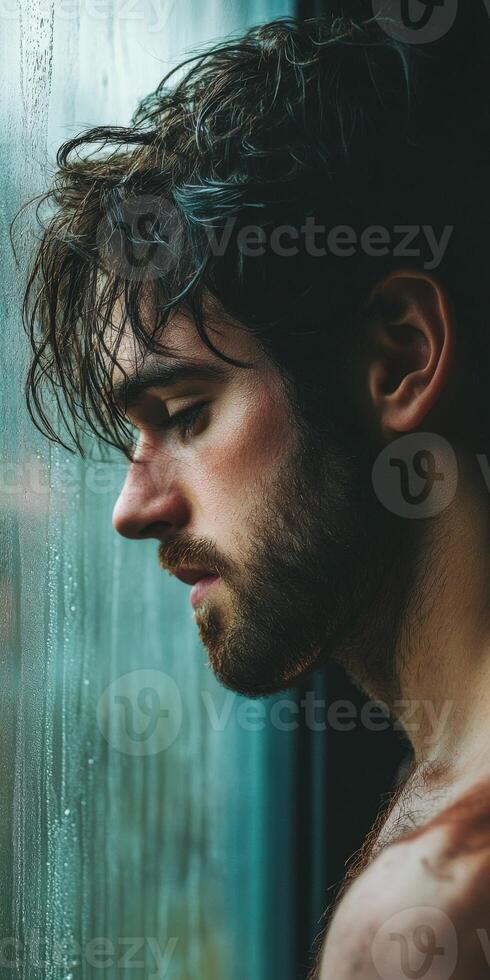 A man with wet hair standing by a window photo