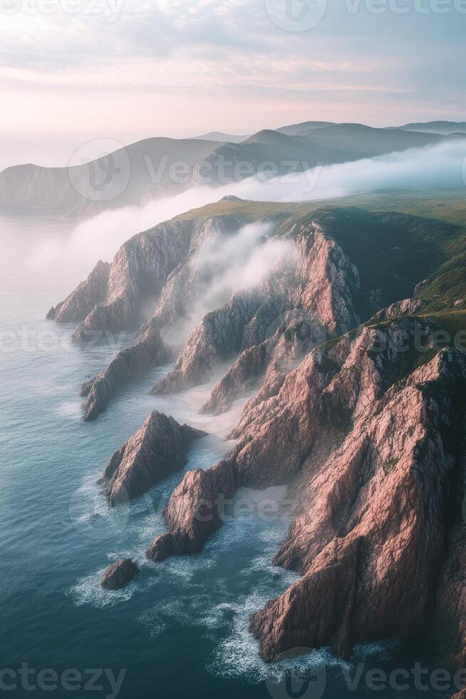 Fog envelops rocky coastline at dawn in serene natural landscape photo
