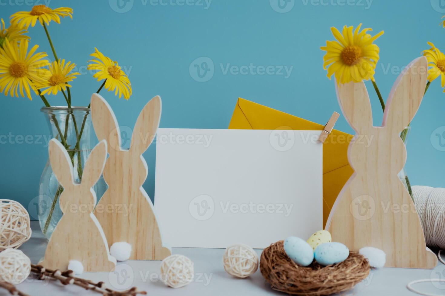 White empty envelope Postcard copy space traditional greeting card to christian holiday. Festive mood composition with bunnies eggs and yellow flowers on pastel blue background. Sustainable natural materials decorations photo