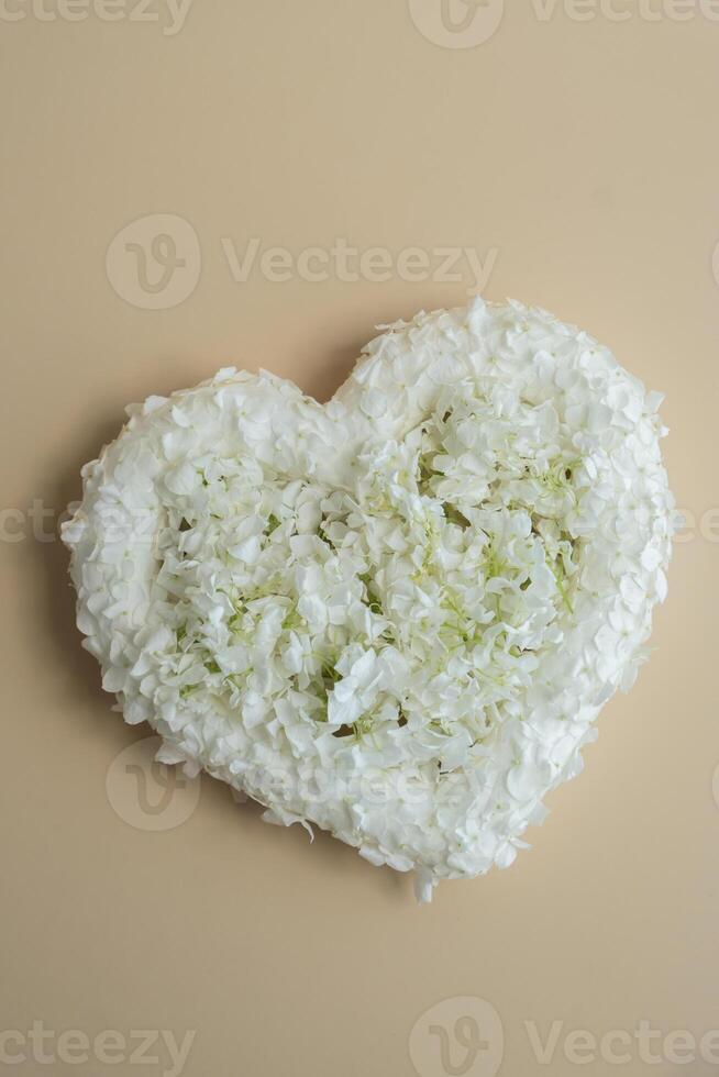 Symbol of love beautiful flower petals in heart shape in beige background. Creative concept of St Valentines day, weeding romantic date or anniversary. Copy space greeting card photo