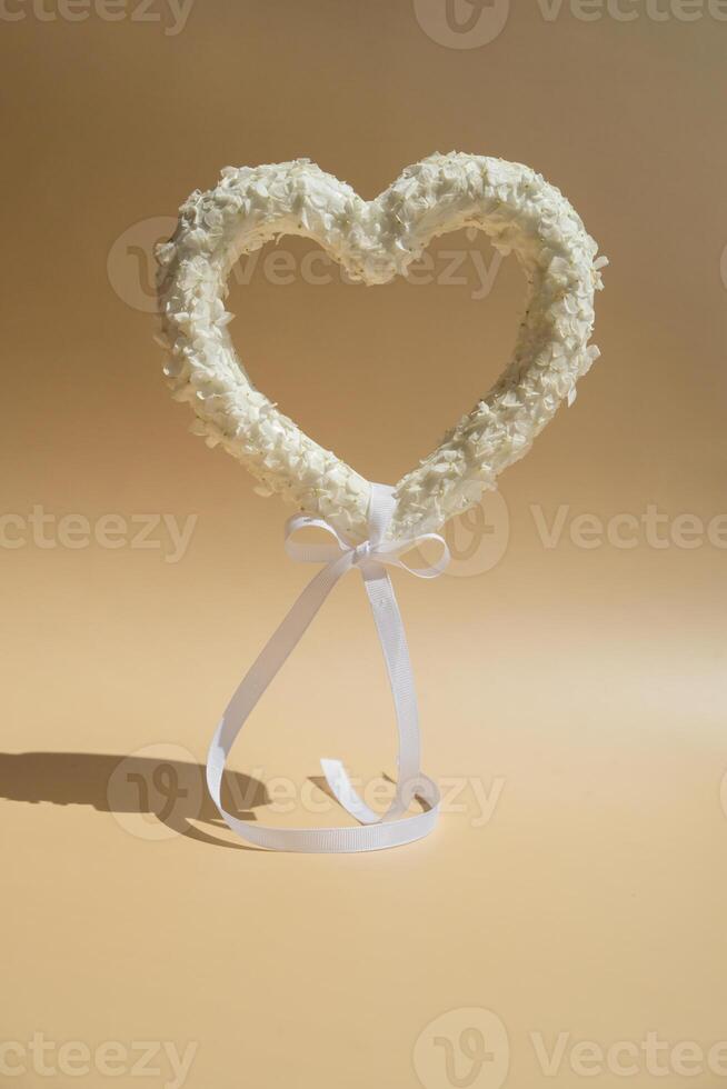 Symbol of love beautiful flower petals in heart shape flying like balloon in beige background. Creative concept of St Valentines day, weeding romantic date or anniversary. Copy space greeting card photo
